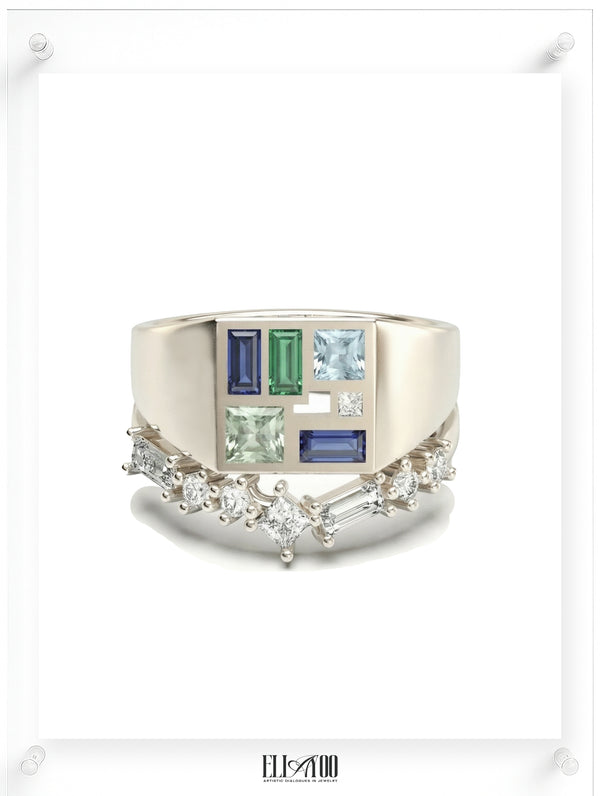 A unique white gold signet ring featuring a mosaic inlay of multi-colored gemstones, paired with a curved diamond wedding band with mixed-cut stones.