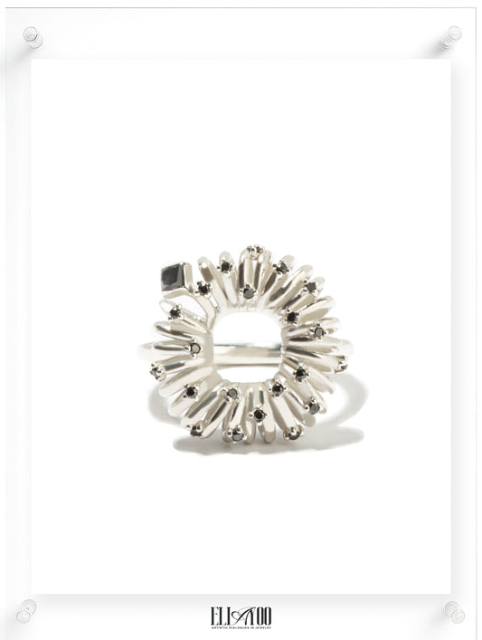 Front view of sculptural silver ring with circular petal setting and black diamond accents