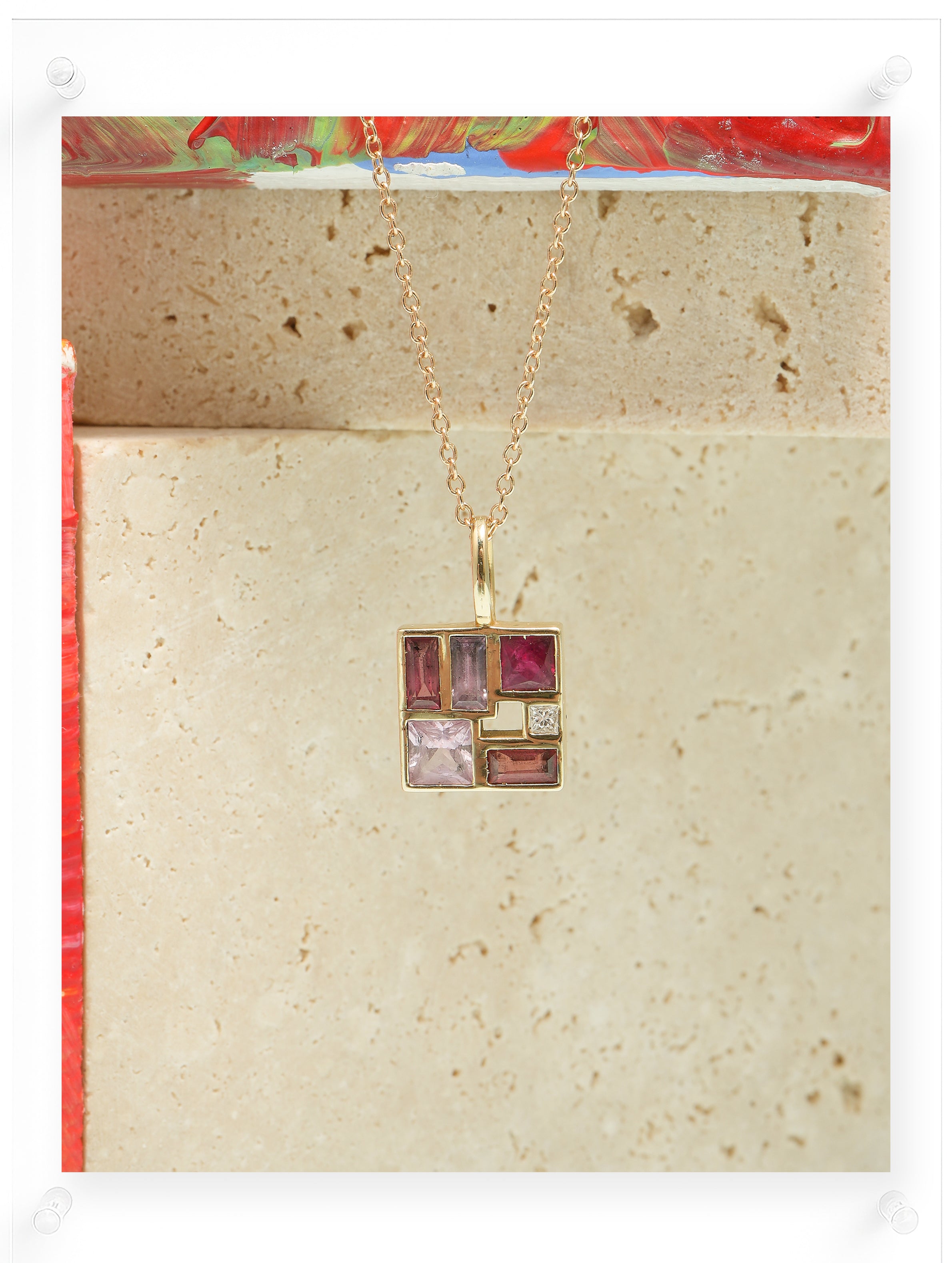 Necklace with a square pendant featuring multicolored stones on a beige card.