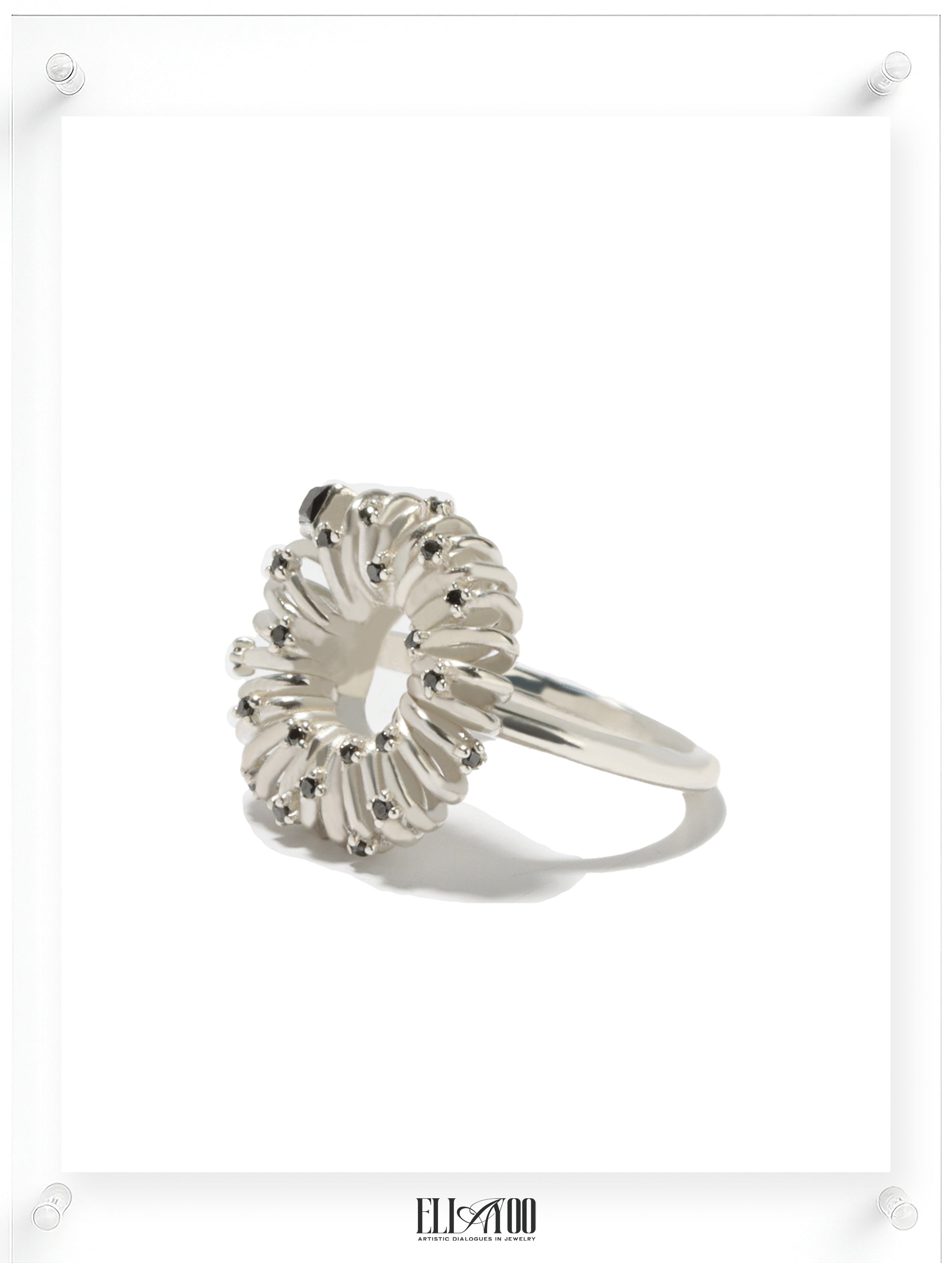 Side view of sculptural silver ring with circular petal setting and black diamond accents