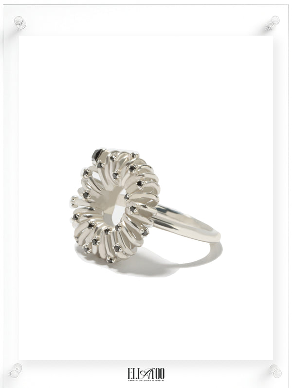 Side view of sculptural silver ring with circular petal setting and black diamond accents