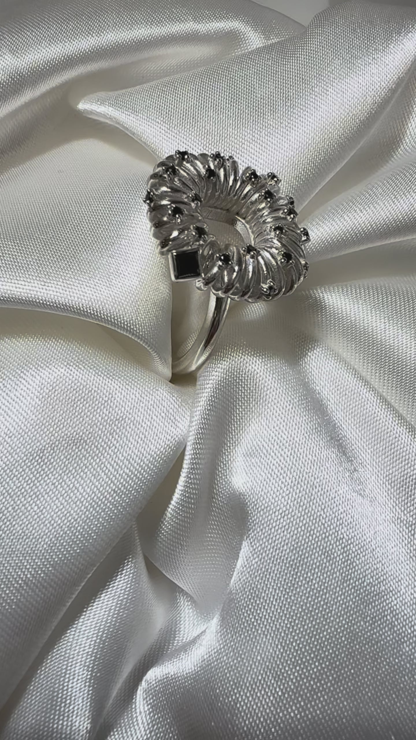 life style video of sculptural silver ring with circular petal setting and black diamond accents